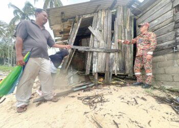 CHIK Amat Ismail (kiri) menunjukkan kerosakan rumahnya dihempas ombak besar di Pantai Bisikan Bayu Semerak, Pasir Puteh, Kelantan semalam. – UTUSAN/TOREK SULONG