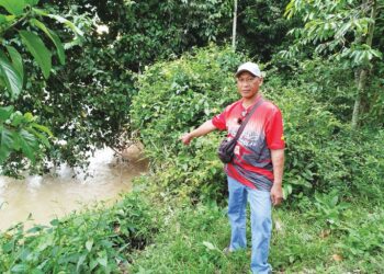 HAMDAN Ibrahim menunjukkan tebing Sungai Pelus yang semakin menghampiri rumahnya akibat hakisan di Kampung Pelador, Sungai Siput, Perak semalam. – UTUSAN/FADZIL ZAINOL