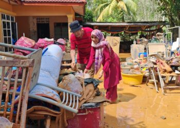 SEORANG penduduk, Masdar Amjang bersama isteri menyusun kelengkapan rumah yang rosak akibat banjir lumpur di Felda Kechau 1 di Lipis, Pahang. - FOTO/NORFARHIZA MOHD. ATAR