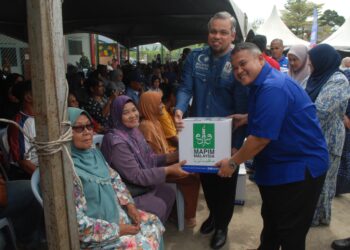 RAIS Yasin menyerahkan kotak makanan kepada seorang penerima selepas merasmikan Jelajah Peduli Ummah di Tanjung Minyak, Melaka. - UTUSAN/AMRAN MULUP