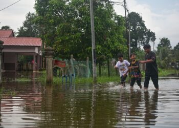 TIGA kanak-kanak mengharungi banjir yang melanda Kampung Rawai, Marang, semalam. - UTUSAN/PUQTRA HAIRRY ROSLI