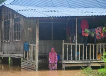 SEORANG wanita warga emas melihat kawasan sekitar rumahnya dilanda banjir di Kampung Matang, Kuala Berang, Hulu Terengganu, hari ini. - UTUSAN/PUQTRA HAIRRY ROSLI