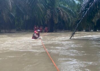 SALAH seorang pekerja ladang yang diperangkap banjir di sebuah ladang kelapa sawit diselamatkan anggota bomba di Kampung Batu Putih, Kerteh, Kemaman, malam tadi. - UTUSAN/NIK NUR IZZATUL HAZWANI NIK ADNAN