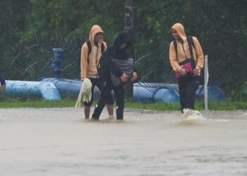 TIGA pelajar meredah air di jalan yang dilanda banjir ke Sekolah Menengah Imtiaz Yayasan Terengganu di Kuala Berang, Hulu Terengganu, hari ini. - UTUSAN/PUQTRA HAIRRY ROSLI