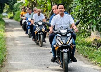 FAHMI Zainol (depan) ketika meninjau kawasan sekitar Pantai Jerejak, Pulau Pinang dengan menaiki motosikal.