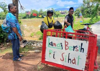 SHAHIDIN Hamid (tengah) mengutip sampah yang dikumpulkan penduduk menggunakan motosikalnya yang diubah suai di Kampung Lanai, Baling, semalam. – UTUSAN/NORLIA RAMLI