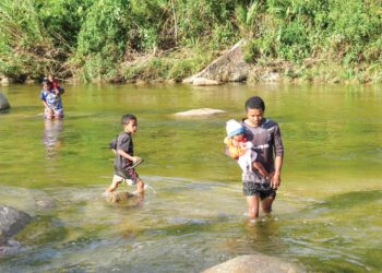 PENDUDUK Orang Asli di tiga kampung di Pos Gob, Gua Musang meredah Sungai Puian kerana ketiadaan jalan penghubung atau jambatan untuk ke kampung berhampiran. – UTUSAN/AIMUNI TUAN LAH