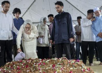 TOH Puan Na'imah Abdul Khalid menyiram air mawar di atas pusara suaminya selepas selamat dikebumikan di Tanah Perkuburan Islam Bukit Kiara, Kuala Lumpur, semalam. - UTUSAN/FARIZ RUSADIO