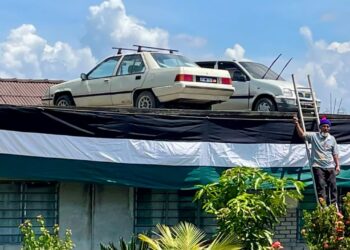 AWANG Ali Abdullah menunjukkan dua keretanya yang diletakkan di atas bumbung rumah di Kampung Matang Paku Ayer Hitam, Jerlun.