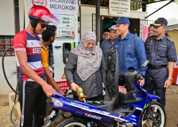 FUZIAH Salleh (tengah) membantu penunggang motosikal mengisi petrol pada
Program Pengedaran Barang Perlu, LPG dan Community Drumming di Kampung Kuala Jengai, Dungun, hari ini.  - UTUSAN/NIK NUR IZZATUL HAZWANI NIK ADNAN