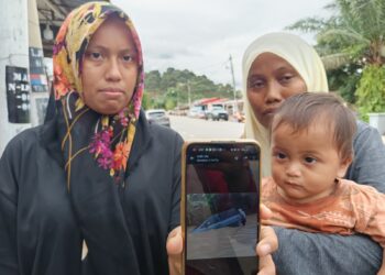 ROHAIDA Razali (kiri) ditemani Nur Hidayah menunjukkan gambar keadaan kenderaan yang dinaikinya yang masih ditenggelami banjir ketika kejadian di Kuala Pilah semalam.-UTUSAN/NOR AINNA HAMZAH.