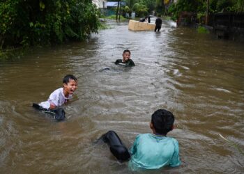 SEKUMPULAN kanak-kanak bermain banjir di Kampung Rawai, Marang.- UTUSAN/PUQTRA HAIRRY ROSLI