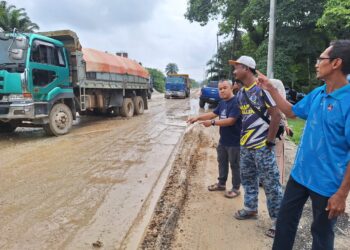 MOHD. Fahmizan Mustakim (kanan) dan penduduk menunjukkan keadaan jalan yang rosak di sekitar Kampung Bukit Kapar, Klang, Selangor, semalam. – UTUSAN / ISKANDAR SHAH MOHAMED