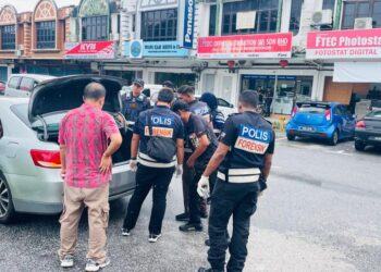 ANGGOTA polis memeriksa kenderaan milik pemilik premis yang kehilangan beg berisi tiga kilogram barang kemas dalam kejadian samun di Jalan Bendahara, Ipoh hari ini. - UTUSAN