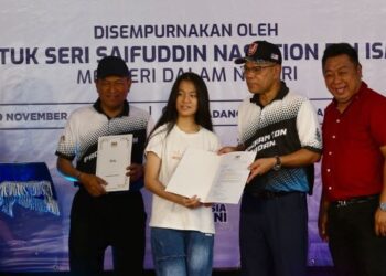 SAIFUDDIN Nasution Ismail menyampaikan sijil warganegara kepada penerima pada Program Sua Mesra KDN di SK Ladang Dublin di Kulim. - UTUSAN/SHAHIR NOORDIN