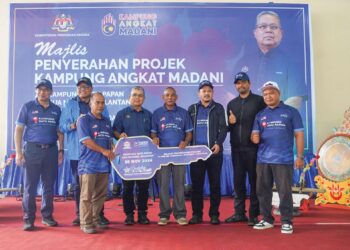 AARON Ago Dagang (empat kiri) menyerahkan replika kunci projek Program Angkat Kampung Madani kepada Ketua KRT Kampung Batu Papan, Awang Idris (empat kanan)  di Kampung Batu Papan, Gua Musang, Kelantan. – UTUSAN/AIMUNI TUAN LAH