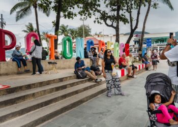 PELANCONG mengambil gambar di hadapan papan tanda Pantai Patong di pinggir Phuket, Thailand.-AFP