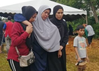 RUZIAH Fuad (tengah) dipapah ahli keluarga ketika hadir pada majlis pengebumian dua anak perempuannya yang mati tertimbus dalam kejadian tanah runtuh di Tanah Perkuburan Islam Kampung Panggung, Ajil, Hulu Terengganu, semalam. - UTUSAN/NOOR HAYATI MAMAT