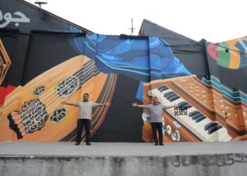  Raven Kumar (kiri) bersama Sharil Nizam Abdul Rahim bergambar pada mural yang memaparkan alat muzik tradisional bersebelahan Gerbang Jalan Tan Hiok Nee, Johor Bahru. - UTUSAN/RAJA JAAFAR ALI