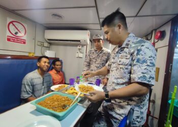 MUHAMMAD Ikmal Hakimi (dua dari kiri) dan Nor Hasrul Abdullah (kiri), 25, ketika dijamu makanan oleh penguatkuasa Maritim sebelum tiba di Jeti Limbongan Kapal Batu Maung, Pulau Pinang hari ini.-UTUSAN/IQBAL HAMDAN