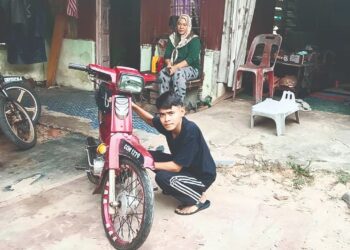 MUHAMMAD Firdaus Hakimi Zulkifli membaiki sebuah motosikal sambil diperhatikan ibunya di Felda Sungai Tekam Utara di Jerantut, Pahang. - UTUSAN/HARIS FADILAH AHMAD