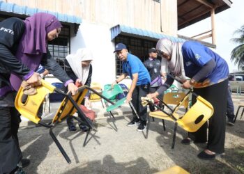 ZALIMAN Sauli bersama kakitangan Universiti Malaysia Perlis (UniMAP) membantu mengangkut kerusi yang rosak ketika membantu kerja-kerja pembersihan di Taman Tabung Haji, Jitra, yang terjejas banjir baru-baru ini.