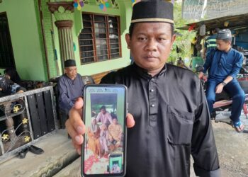 MOHD.  NAZIM Md. Yusuf menunjukkan gambar kenangan Allahyarham ibu, ayah serta adiknya bersama Athiyyah Nur Sofia ketika ditemui di rumah orang tuanya di Felcra Sungai Ara, Kota Tinggi.