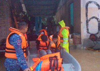 ANGGOTA Angkatan Pertahanan Awam (APM) melaksanakan operasj menyelamat mangsa banjir di kawasan yang mula dinaiki air di Machang, Kelantan. - IHSAN APM