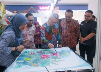 RAZALI Idris (tengah) mencuba mencanting batik semasa melawat reruai jualan pada Karnival Beautiful Terengganu 2025 di Kuala Terengganu, Terengganu hari ini.