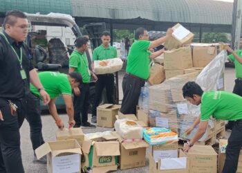 MAS IMRAN Adam (tengah) membantu pekerja Econsave menyusun pelbagai barangan sumbangan orang ramai yang akan dihantar bagi membantu mangsa banjir di negeri-negeri Pantai Timur di Pasaraya Econsave Senai, Kulai.