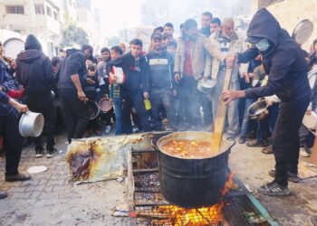 Anggota sukarelawan memasak makanan yang disumbangkan oleh pelbagai pertubuhan antarabangsa di Kem al-Shati, Gaza. – AFP