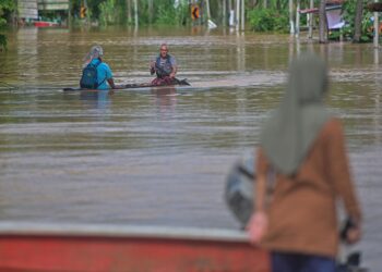 PENDUDUK menaiki sampan untuk meninjau situasi banjir di Kampung Matang, Hulu Terengganu. - UTUSAN/PUQTRA HAIRRY ROSLI