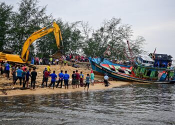 NELAYAN bergotong-royong mengalihkan bot nelayan yang dihanyutkan dalam kejadian fenomena ombak besar di Kampung Telaga Papan, Setiu, hari ini.  - UTUSAN/PUQTRA HAIRRY ROSLI