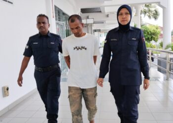 TERTUDUH diiringi anggota polis ketika dihadapkan di Mahkamah Majistret, Alor Gajah, Melaka. - UTUSAN/MUHAMMAD SHAHIZAM TAZALI