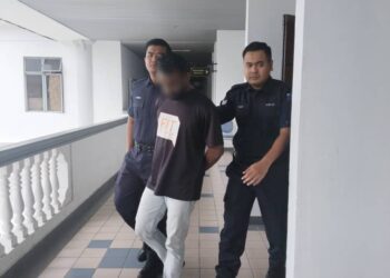 TERTUDUH diiringi polis ketika dihadapkan ke Mahkamah Sesyen, Ayer Keroh, Melaka. - UTUSAN/MUHAMMAD SHAHIZAM TAZALI