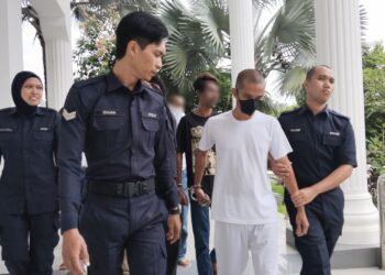 TERTUDUH diiringi anggota polis ketika dibawa ke Mahkamah Majistret, Alor Gajah, Melaka. - UTUSAN/MUHAMMAD SHAHIZAM TAZALI