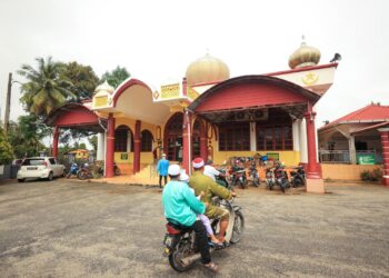 PENDUDUK menunggang motosikal ke masjid untuk menunaikan solat Jumaat selepas banjir yang melanda Mukim Bendang Pak Yong, Tumpat, Kelantan surut sepenuhnya. -UTUSAN/KAMARUL BISMI KAMARUZAMAN