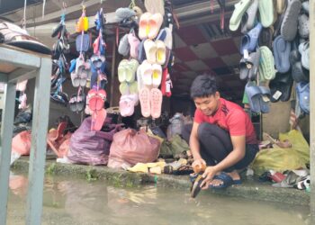 PENIAGA membersihkan selipar dan premis perniagaan yang ditenggelami banjir di Zon Bebas Cukai, Rantau Panjang, Kelantan-UTUSAN/ROHANA ISMAIL.