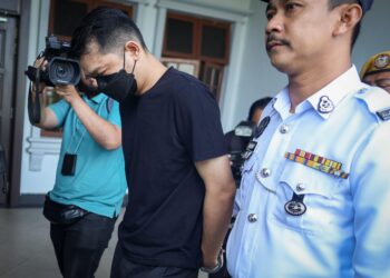 Anggota polis mengiringi seorang lelaki yang terbabit dalam kemalangan langgar lari di Lebuhraya SPE bagi menghadapi tuduhan di Mahkamah Majistret Kuala Lumpur.-UTUSAN/Saddam Yusoff