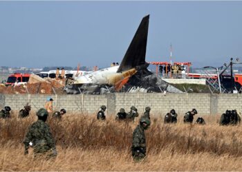 Anggota tentera Korea Selatan mencari mayat mangsa berhampiran bangkai pesawat Boeing 737-800 Jeju Air yang  tergelincir dan meletup selepas merempuh tembok penghadang ketika mendarat di Lapangan Terbang Antarabangsa Muan, semalam. – AFP