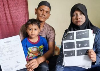 NORWAHIDA Abdul Ghani bersama suami, Ibrahim Zakaria menunjukkan surat pengesahan penyakit hati kronik yang dihidapi wanita itu di Kampung Kuala Kechau, Lipis, Pahang.