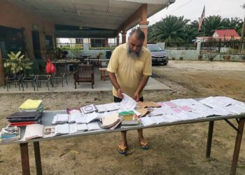 MOHD. Asman Abdul Hamid menjemur al-Quran dan kitab-kitab lama yang rosak akibat banjir di Sikh Settlemen di Batu 10 Jalan Tanjung Tualang di Batu Gajah, Perak. - UTUSAN/AIN SAFRE BIDIN