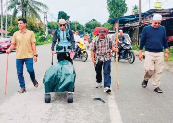 MOHAMAD Al-Bukhari Ellia (dua dari kiri) dan Mohamad Azizul Abdullah (dua dari kanan) diiringi beberapa penduduk kampung memulakan misi berjalan kaki dari Changkat Lobak di Bagan Serai ke Mekah, semalam. – UTUSAN/WAT KAMAL ABAS