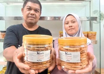 SHAHARULNIZAM Ahmad dan isteri, Raffezah Md. Isa menunjukkan kuih kapit dihasilkannya.  – UTUSAN/MEGAT LUTFI MEGAT RAHIM