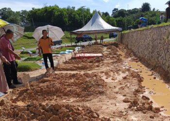 NORHAYATI Embal dan waris keluarga yang kini menjadi sukarelawan Lot C, Tanah Perkuburan Islam Senawang, Seremban, melihat keadaan selepas pusara digenangi air, semalam. - FOTO/NOR AINNA HAMZAH