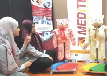 ASNIDAH Abd. Wahab (dua dari kiri) menunjukkan robot ciptaannya yang dapat membantu mengajar pergerakan bagi kanak-kanak autisme di UTM Skudai, Johor Bahru.