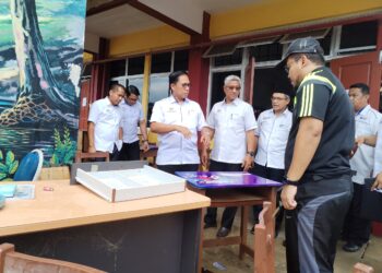 AZMAN Adnan (tiga dari kiri) melihat  kerosakan bahan-bahan  pembelajaran serta peralatan sekolah yang musnah ditenggelami banjir di Sekolah Menengah Kebangsaan Bukit Payung di Besut, Terengganu.