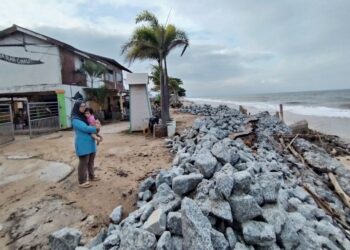 NOR Suhana Zakaria melihat benteng batu dibina di belakang chaletnya yang sebelum ini musnah akibat hakisan di Pantai Teluk Bayu, Kuala Besut, Terengganu.