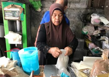 NURULAIN Mohamad membungkus santan segar di kedai runcitnya di Kota Bharu, Kelantan.- UTUSAN/ ROSLIZA MOHAMED