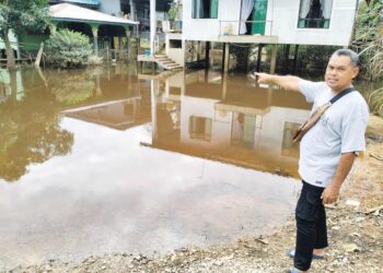 MOHD. Nordin Yusof menunjukkan kawasan rumah penduduk yang masih digenangi banjir termenung di Kampung Tersang, Rantau Panjang, Kelantan. - UTUSAN/ROHANA ISMAIL